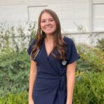 female wearing a navy blue dress and a stethoscope around her neck